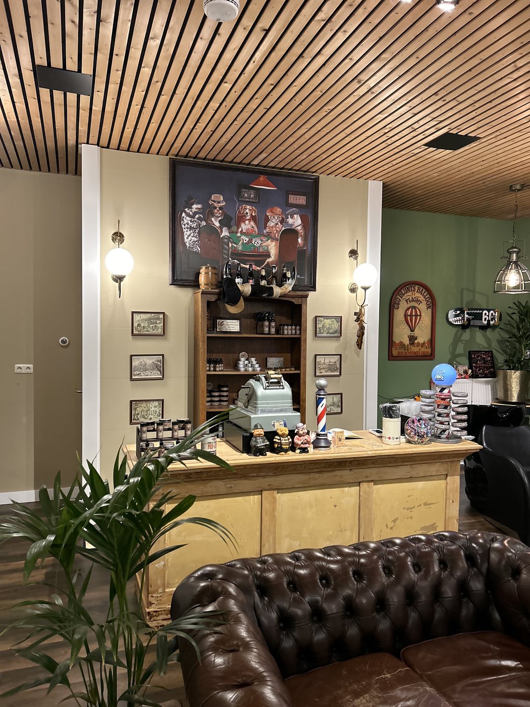 De wachtruimte van Classic Clips: een houten balie, een leren chesterfield, ingelijste prenten en een barberpaal