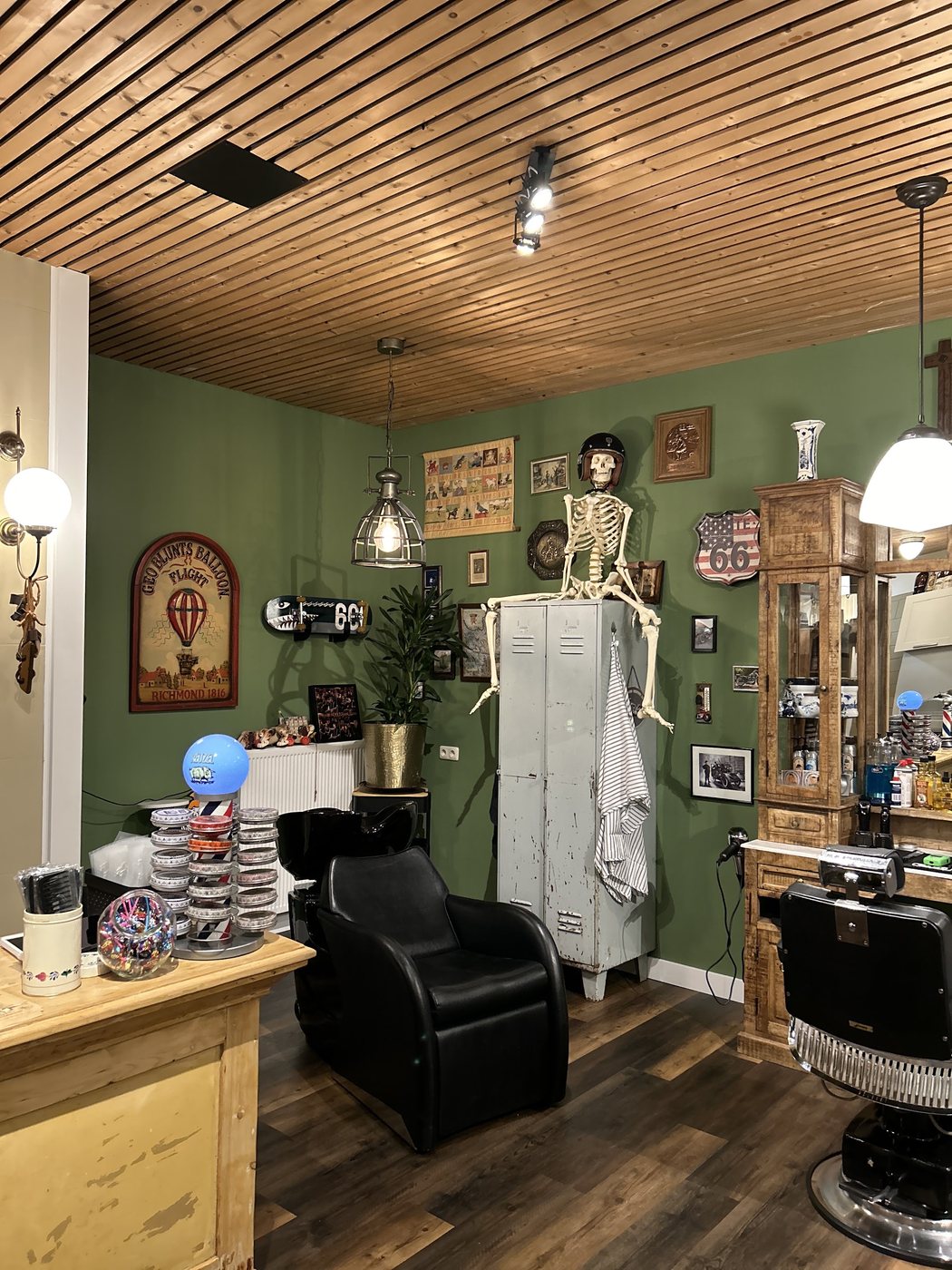 Hoek van de zaak met een wasstoel, een vitrine met producten, oude reclameborden en een skelet